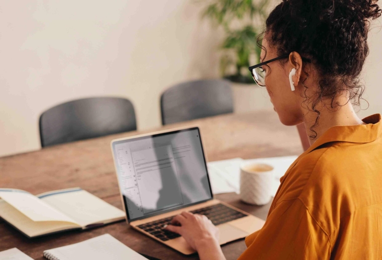 Femme qui utilise un ordinateur portable pour son travail d'immobilier a domicile