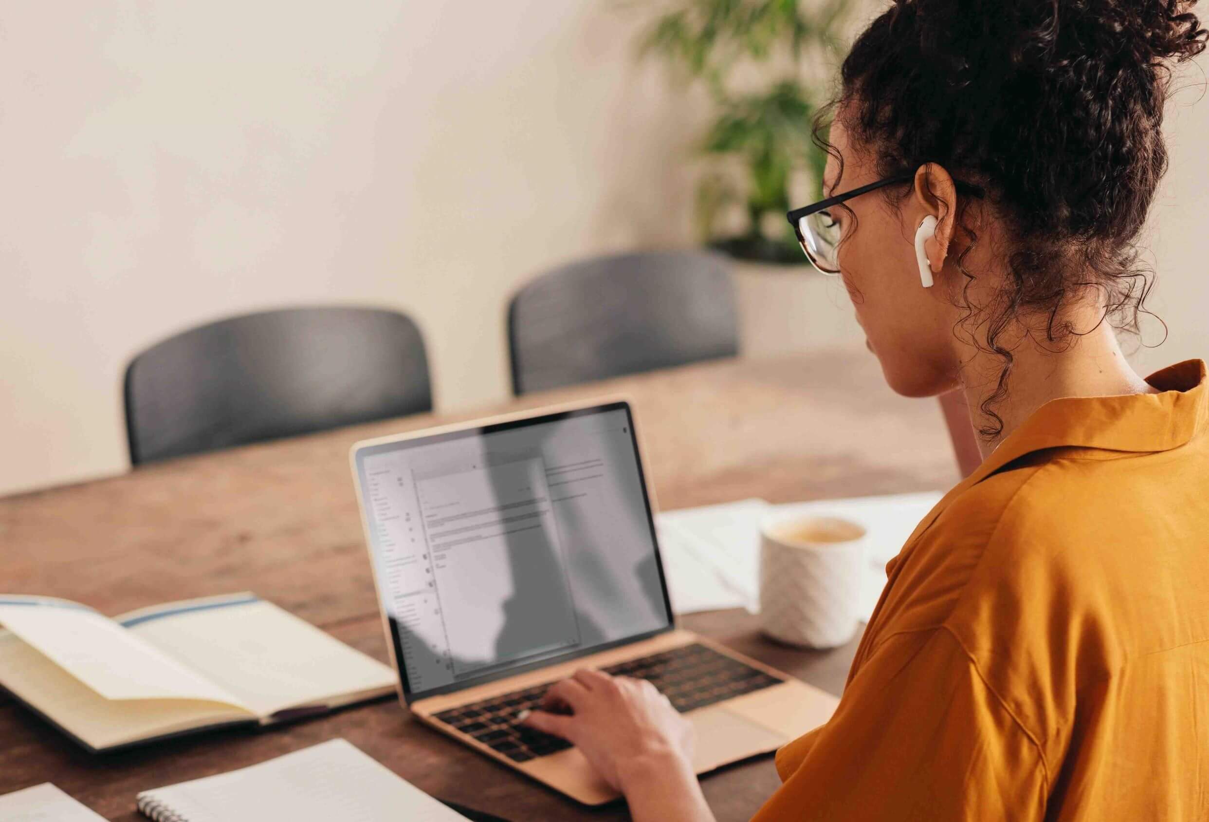 Femme qui utilise un ordinateur portable pour son travail d'immobilier a domicile