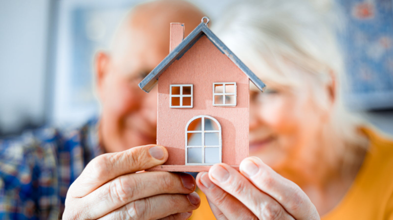 Couple senior tenant une maquette de maison, symbole de vente en viager ou de transmission de patrimoine immobili